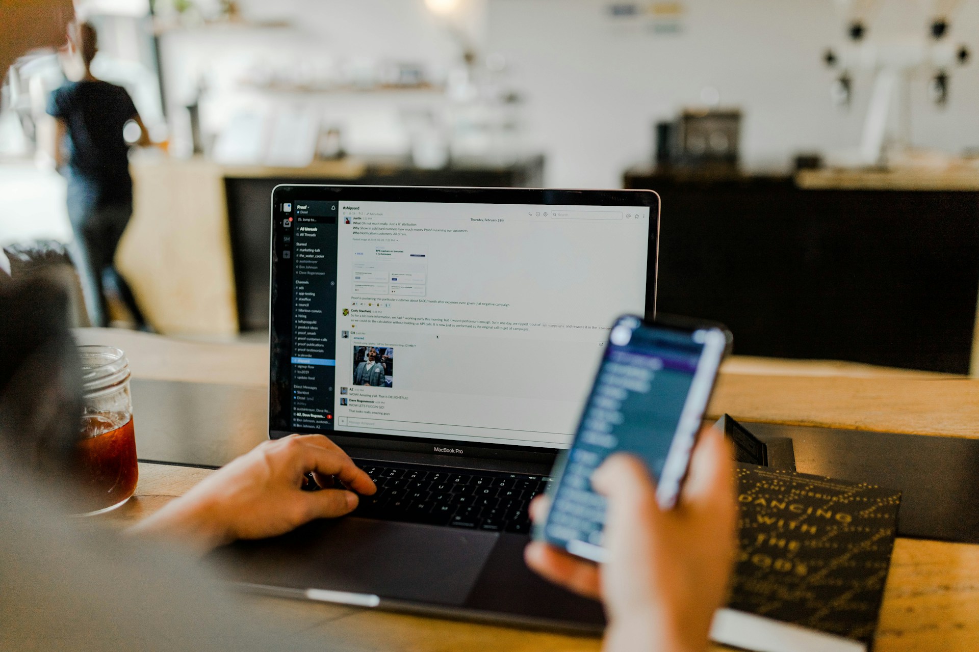 Person using laptop and smartphone in café workspace